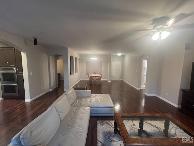 living room with baseboards, arched walkways, wood finished floors, and ceiling fan with notable chandelier