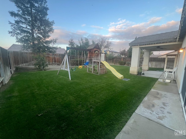 view of playground with a fenced backyard, a lawn, and a patio