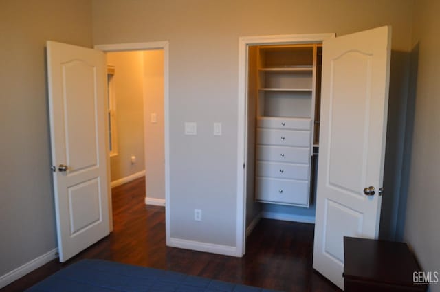 unfurnished bedroom with baseboards and dark wood-style flooring