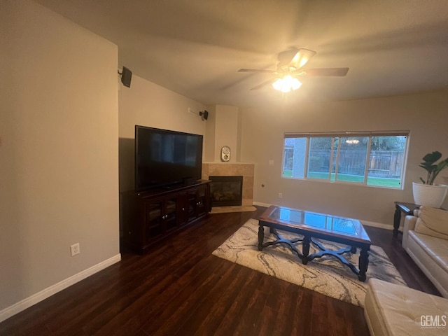 living room featuring ceiling fan, a tile fireplace, wood finished floors, and baseboards