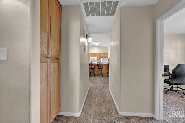 hallway with carpet floors, visible vents, and baseboards