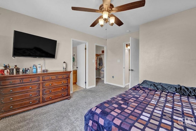 carpeted bedroom with a ceiling fan, baseboards, a spacious closet, a closet, and ensuite bath