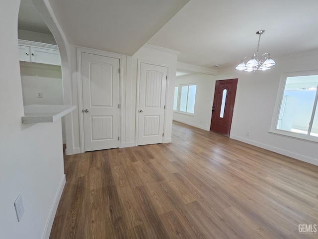 interior space featuring light hardwood / wood-style floors, ornamental molding, and an inviting chandelier