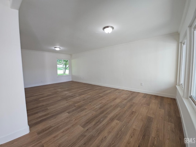 empty room with ornamental molding and dark wood-type flooring