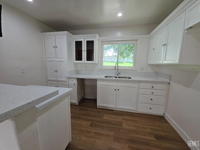 kitchen featuring dark hardwood / wood-style flooring, white cabinetry, sink, and light stone counters