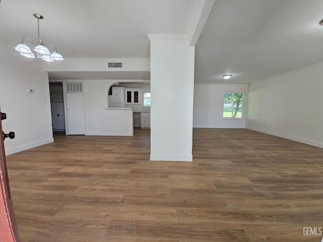 unfurnished living room featuring hardwood / wood-style flooring, an inviting chandelier, and crown molding