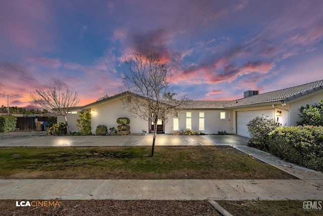 single story home with a yard, cooling unit, and a garage