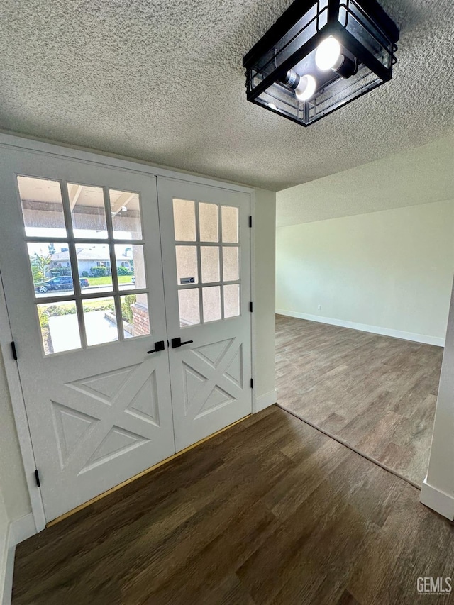 doorway to outside featuring dark wood-type flooring, a textured ceiling, and french doors