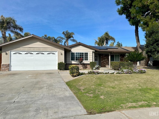 ranch-style home with a garage, a front yard, and solar panels