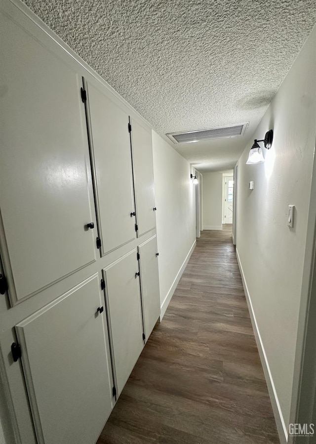 hallway featuring dark wood-type flooring and a textured ceiling