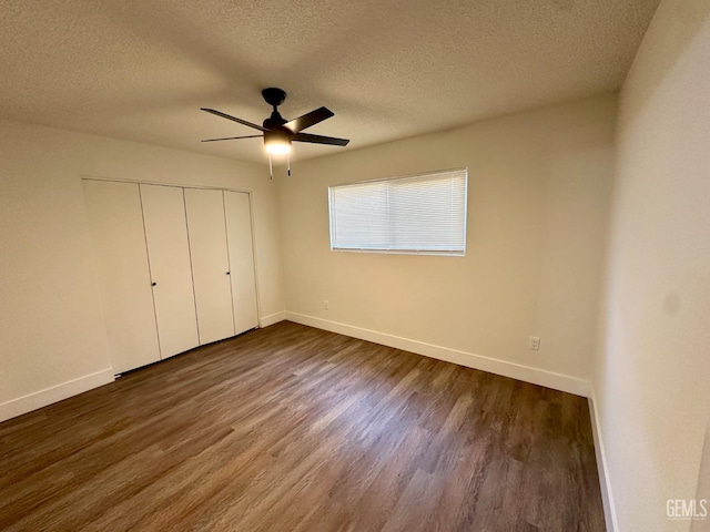 unfurnished bedroom with ceiling fan, dark hardwood / wood-style flooring, a closet, and a textured ceiling