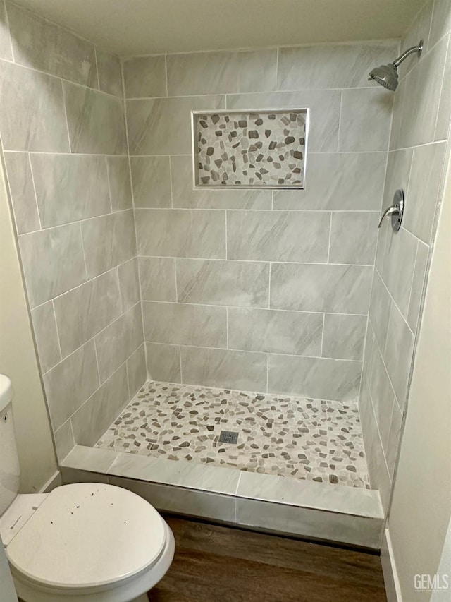 bathroom with tiled shower, hardwood / wood-style floors, and toilet