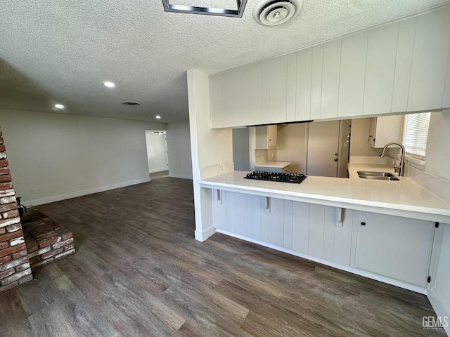 kitchen with black gas cooktop, sink, dark hardwood / wood-style flooring, kitchen peninsula, and a textured ceiling