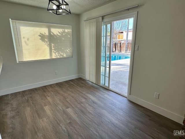 unfurnished dining area with dark wood-type flooring and a textured ceiling