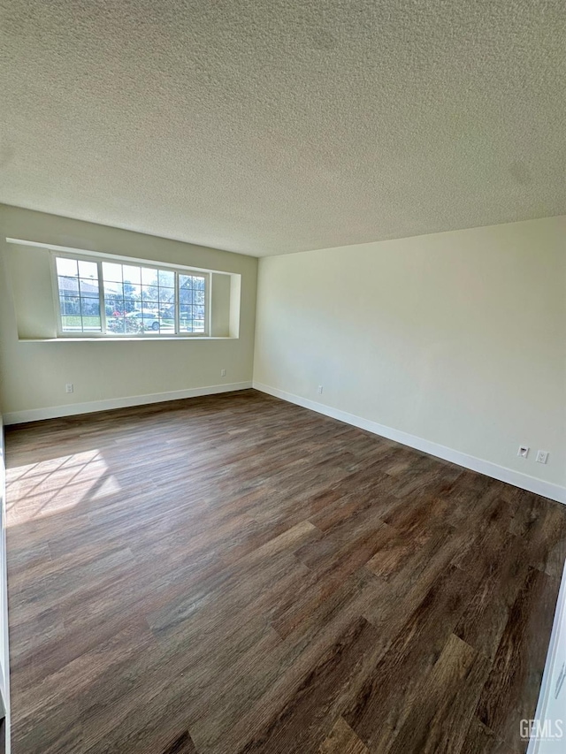 unfurnished room featuring dark hardwood / wood-style flooring and a textured ceiling