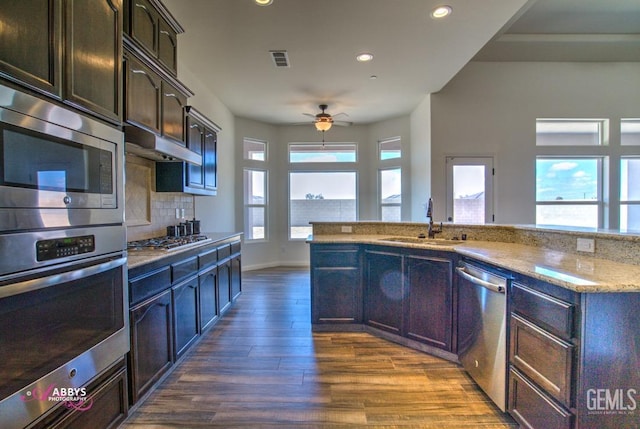 kitchen with sink, appliances with stainless steel finishes, dark hardwood / wood-style flooring, ceiling fan, and decorative backsplash