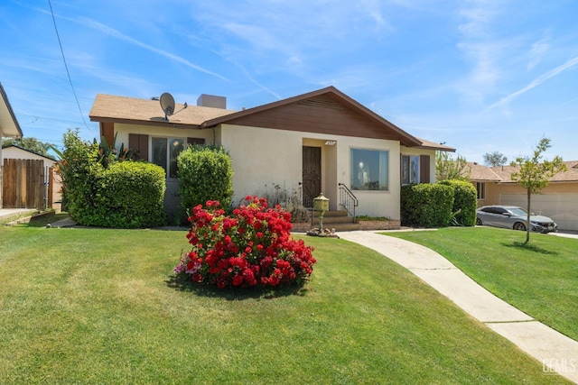 view of front of property with stucco siding, fence, a front lawn, and a garage
