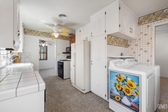 kitchen featuring range with gas stovetop, a sink, washer and clothes dryer, tile countertops, and freestanding refrigerator