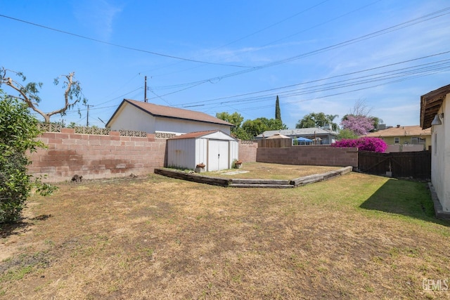 view of yard featuring a storage shed, an outdoor structure, and a fenced backyard