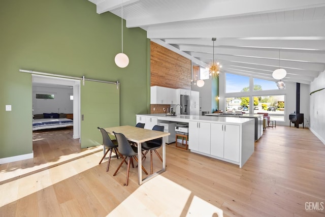 662 Woodland Ct, Arroyo Grande, CA 93420 - kitchen featuring a barn door, beamed ceiling, white cabinetry, light wood finished floors, and decorative light fixtures
