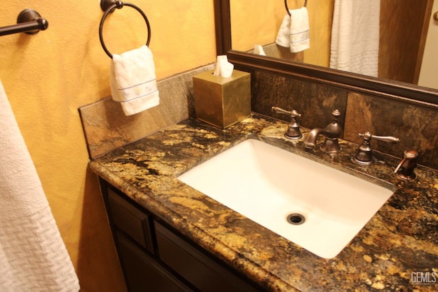 bathroom with a textured wall, vanity, and decorative backsplash