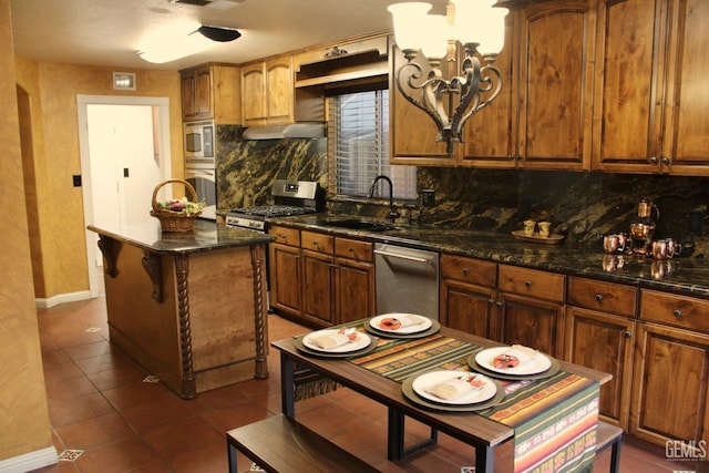 kitchen featuring decorative backsplash, a sink, appliances with stainless steel finishes, baseboards, and dark tile patterned floors