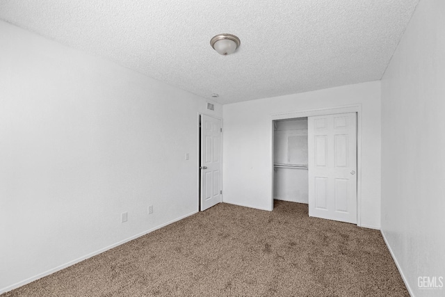 unfurnished bedroom featuring dark colored carpet, a textured ceiling, and a closet