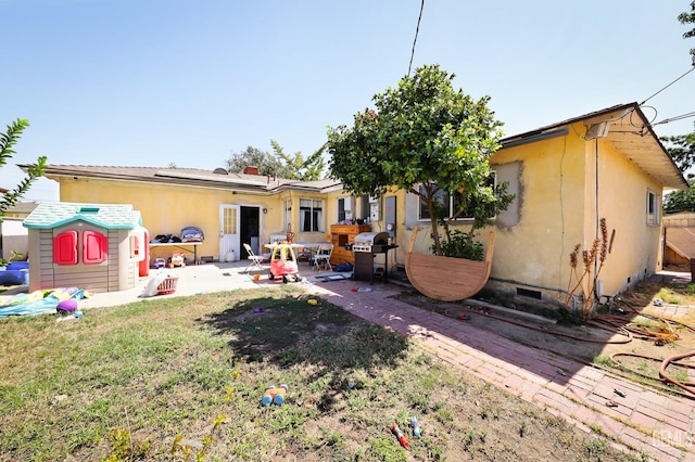 back of property with a lawn, solar panels, and a patio