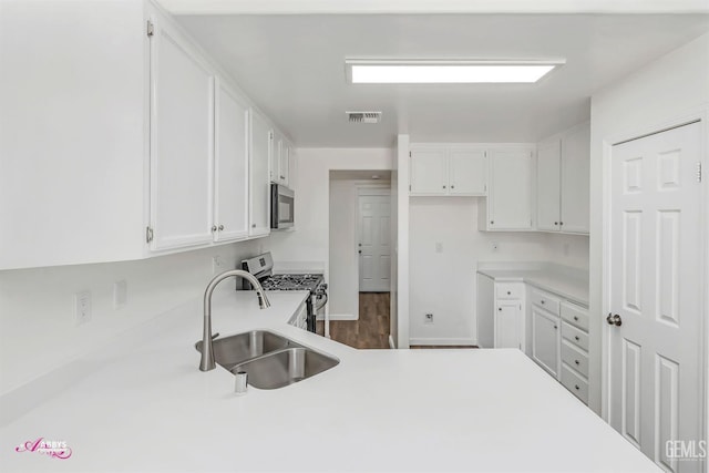 kitchen featuring appliances with stainless steel finishes, white cabinets, light countertops, and dark wood finished floors