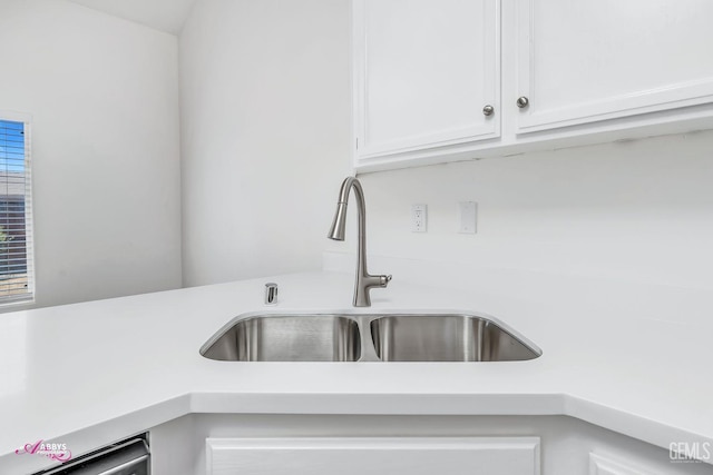 kitchen view of light countertops, white cabinetry, and dishwasher