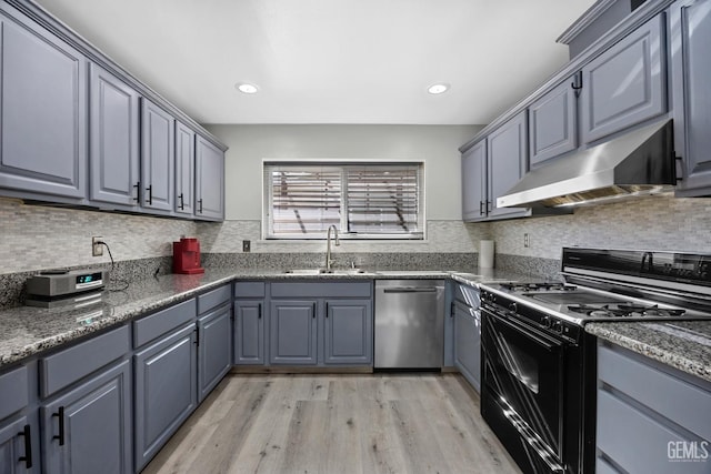 kitchen with stainless steel dishwasher, wall chimney range hood, light wood-type flooring, sink, and black gas range