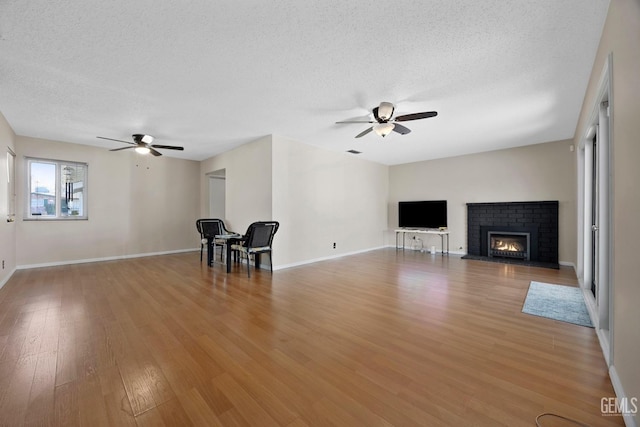 unfurnished living room with light hardwood / wood-style floors, a textured ceiling, and ceiling fan