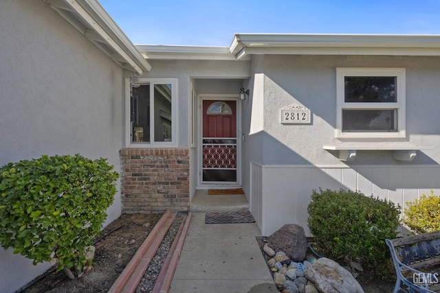 entrance to property featuring brick siding and stucco siding