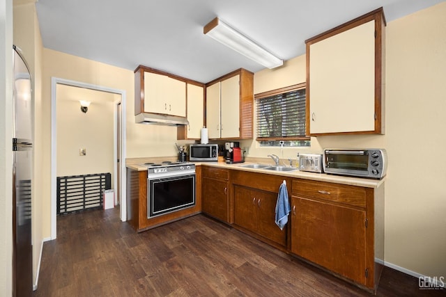 kitchen featuring dark wood-type flooring, stainless steel microwave, a sink, oven, and a toaster