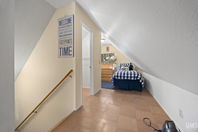 bedroom featuring baseboards, a textured ceiling, and vaulted ceiling
