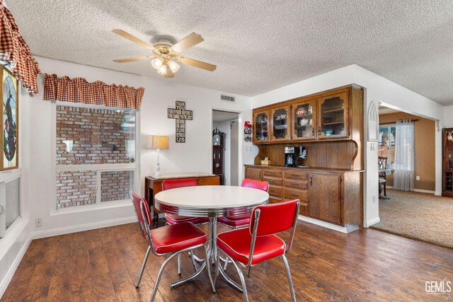 dining room with a textured ceiling, ceiling fan, and dark wood-type flooring