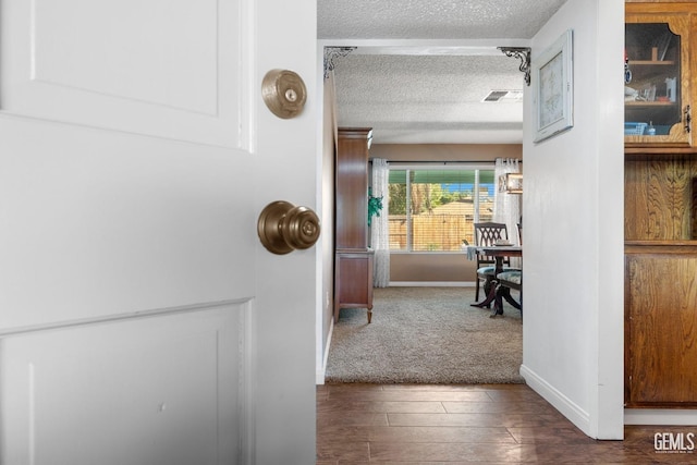 hallway featuring dark hardwood / wood-style flooring and a textured ceiling