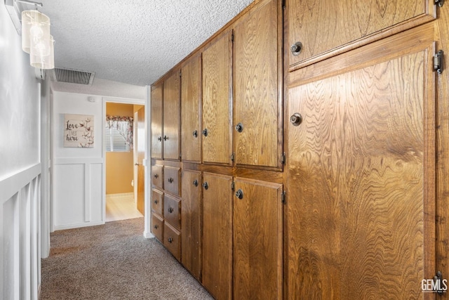 hallway with light colored carpet and a textured ceiling