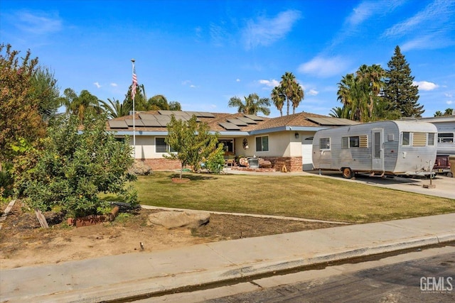 view of front of home featuring solar panels and a front yard