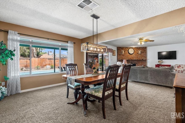 carpeted dining space featuring a textured ceiling, a brick fireplace, and ceiling fan