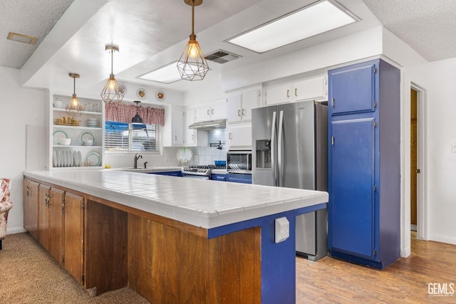 kitchen featuring white cabinets, pendant lighting, stainless steel appliances, and tile counters