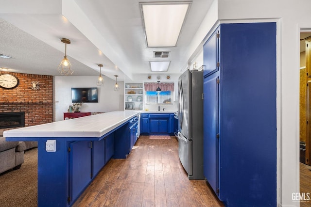 kitchen with kitchen peninsula, stainless steel fridge, blue cabinetry, and a kitchen breakfast bar