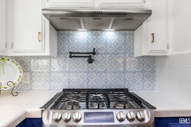 kitchen featuring white cabinetry, decorative backsplash, tile counters, and extractor fan