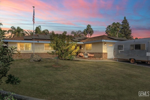 single story home with solar panels, a garage, and a yard