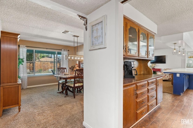 kitchen with pendant lighting, carpet floors, and a textured ceiling