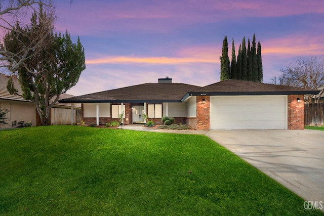 view of front of home with brick siding, a lawn, driveway, and fence