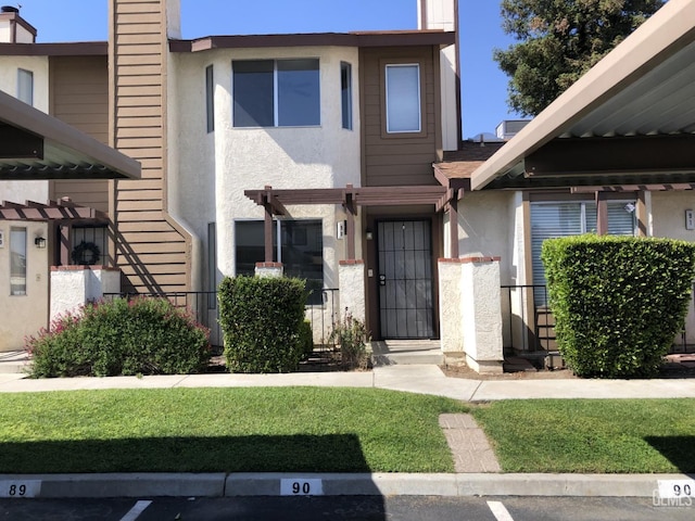view of property featuring covered parking, a chimney, and stucco siding