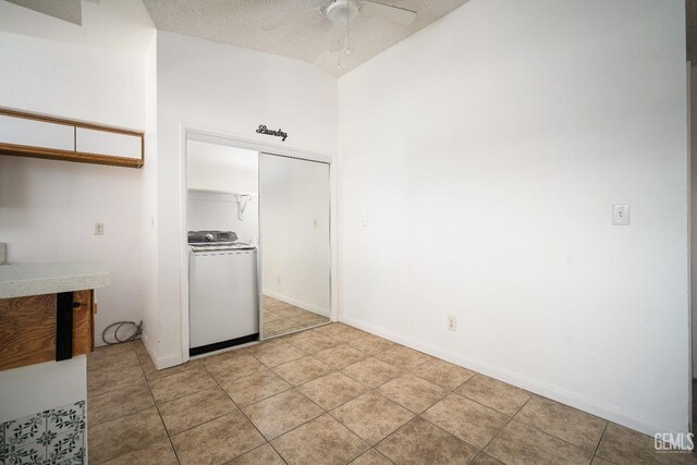 kitchen with a textured ceiling, light tile patterned floors, lofted ceiling, washer / dryer, and ceiling fan