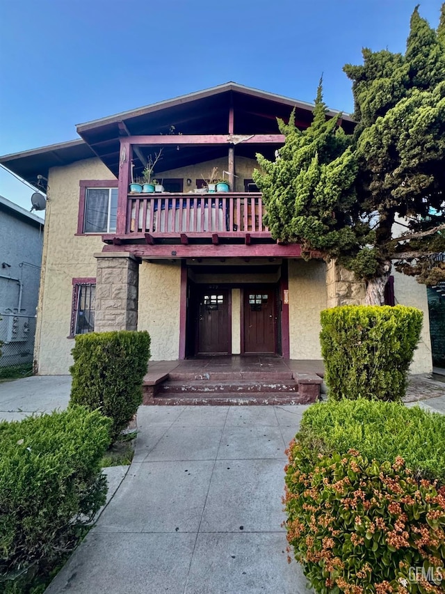 view of front of home with stucco siding and a balcony