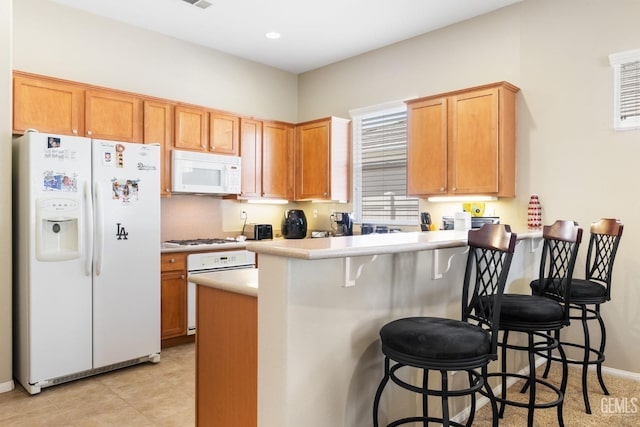 kitchen featuring a breakfast bar, white appliances, and kitchen peninsula